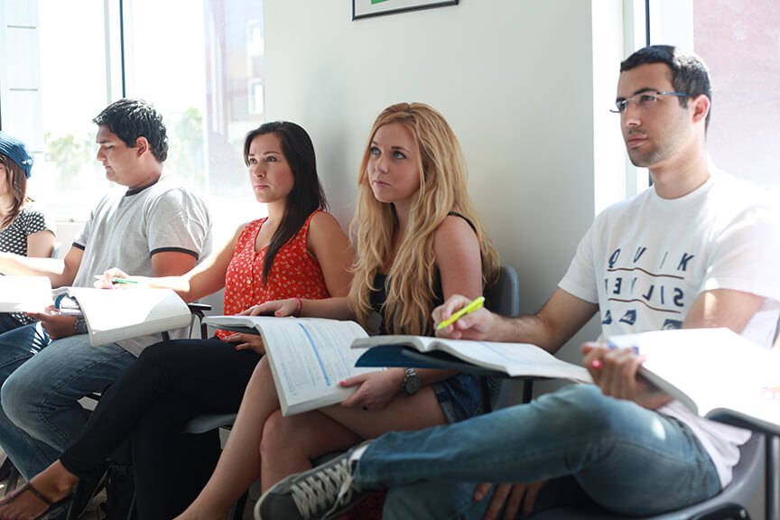 Learners study with coursebooks in a bright classroom