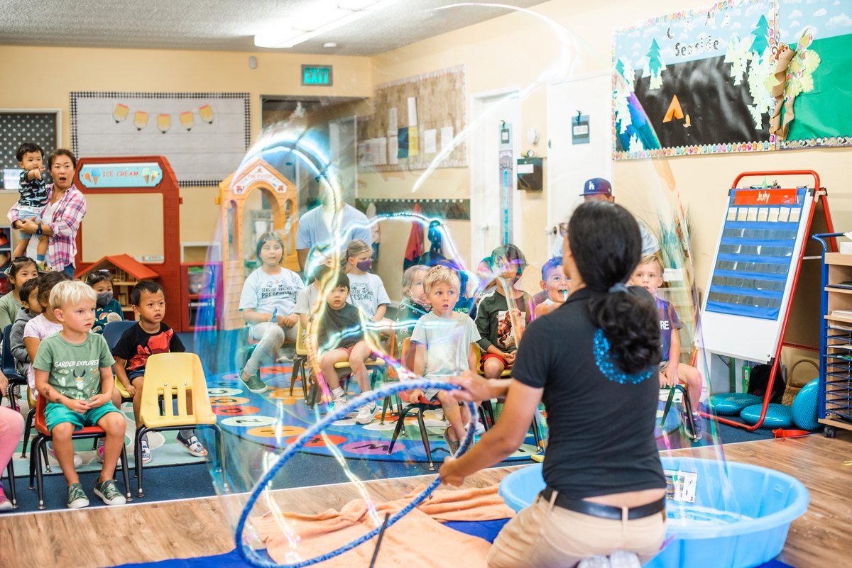 Children join an adult-led bubble activity in a preschool classroom