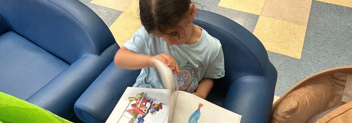 A child explores a picture book in the reading corner